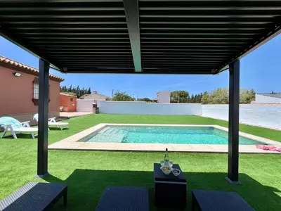 a swimming pool in a yard with awning over it at Chalet Wanderlust in Chiclana de la Frontera