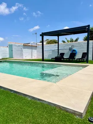 a swimming pool with two chairs and a gazebo at Chalet Wanderlust in Chiclana de la Frontera