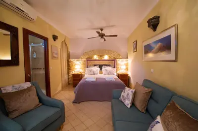 a bedroom with a bed and two blue chairs at La Vista de Medina Studios & Apartments in Medina Sidonia