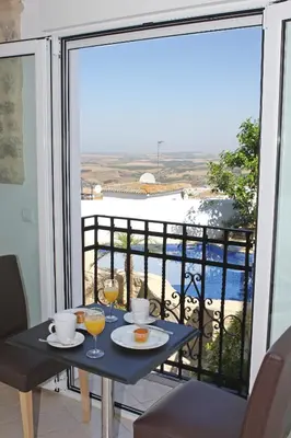 a table with two glasses of wine on a balcony at La Vista de Medina Studios & Apartments in Medina Sidonia