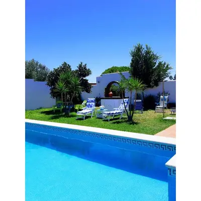 a view of a swimming pool with chairs and a house at Villa Lola 14 in Chiclana de la Frontera