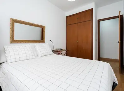 a bedroom with a white bed and a wooden cabinet at Apartoyou - Plaza San Juan in El Puerto de Santa María