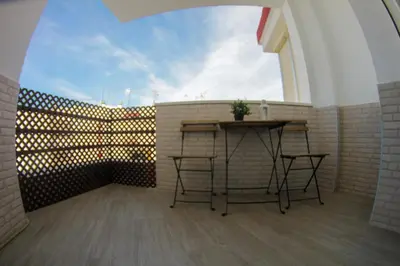 a balcony with a table and a brick wall at Apartamento Piletas in Sanlúcar de Barrameda