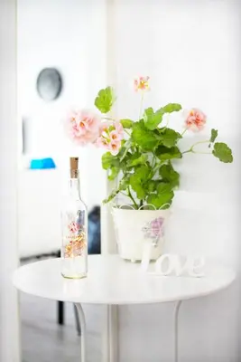 a white table with a bottle and a potted plant at Apartamento Piletas in Sanlúcar de Barrameda