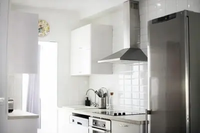a white kitchen with a stainless steel refrigerator at Apartamento Piletas in Sanlúcar de Barrameda