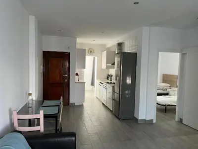 a kitchen and a living room with a table and chairs at Apartamento Piletas in Sanlúcar de Barrameda