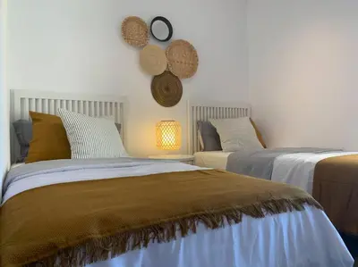a bedroom with two beds and a clock on the wall at Azvalia - Valdelagrana Mirador de la Bahía, Playa, piscina, parking, vistas ! in El Puerto de Santa María