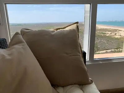 a couch with a pillow in front of a window at Azvalia - Valdelagrana Mirador de la Bahía, Playa, piscina, parking, vistas ! in El Puerto de Santa María