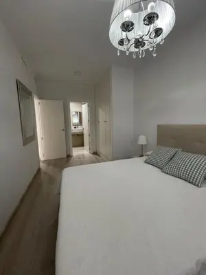 a bedroom with a large white bed and a chandelier at BAJO GUÍA DELUXE in Sanlúcar de Barrameda