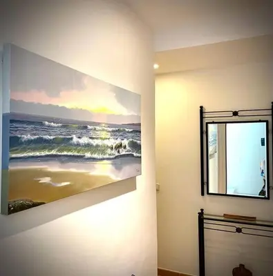 a painting of the ocean on a wall next to a window at MyChoice Dadim in Rota