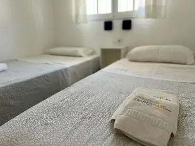 two beds in a white room with a towel on them at Apartamento Columela in Chiclana de la Frontera