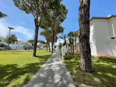 a path through a park with trees and buildings at Apartamento Columela in Chiclana de la Frontera