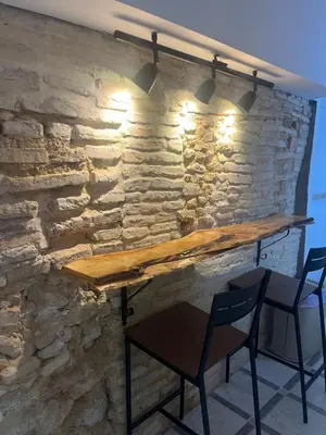 a stone wall with a wooden table and chairs at Apartamentos Arquillo de Rota in Sanlúcar de Barrameda