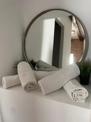 a pile of towels on a counter in front of a mirror at Apartamentos Arquillo de Rota in Sanlúcar de Barrameda