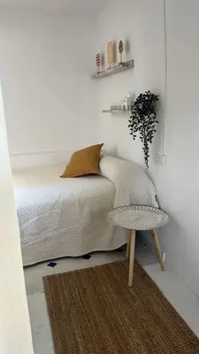 a white bedroom with a bed and a table at Apartamentos Arquillo de Rota in Sanlúcar de Barrameda