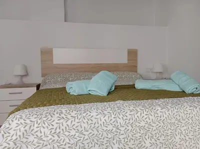 a bed with two blue pillows on top of it at Apartamento Peonía in Jerez de la Frontera