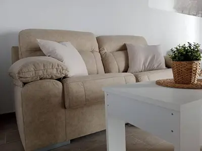 a brown couch with pillows and a white table at Apartamento Peonía in Jerez de la Frontera