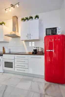 a red refrigerator in a kitchen with white cabinets at Apartamento Obispo centro Jerez de la Frontera in Jerez de la Frontera
