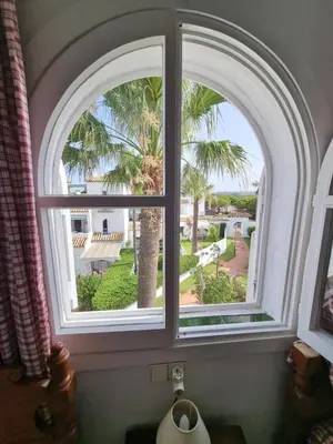 an arched window with a view of a palm tree at Victoria Costa Sancti Petri in Novo Sancti Petri