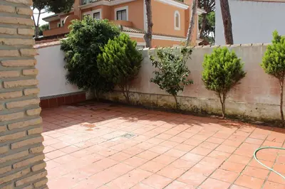 a brick wall and a brick courtyard with trees at Chalet Violeta in Chiclana de la Frontera