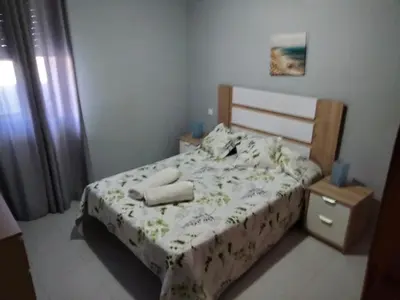 a small bedroom with a bed with white sheets and flowers at APART CLUB LABARROSA in Chiclana de la Frontera