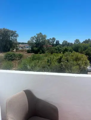 a chair sitting on a balcony with a view of trees at APART CLUB LABARROSA in Chiclana de la Frontera