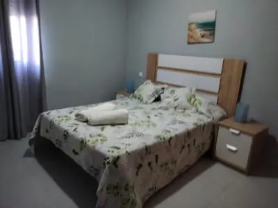 a bedroom with a bed with a wooden headboard and a table at APART CLUB LABARROSA in Chiclana de la Frontera