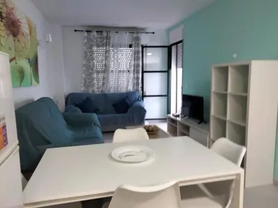 a living room with a white table and a blue couch at APART CLUB LABARROSA in Chiclana de la Frontera