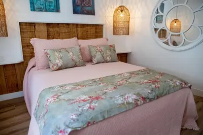 a bedroom with a bed with pink sheets and pillows at Apartamentos Milord in El Puerto de Santa María