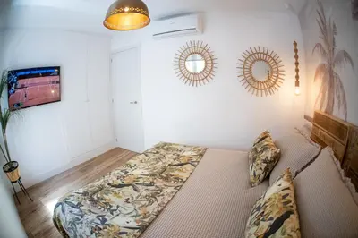 a bedroom with a bed and two mirrors on the wall at Apartamentos Milord in El Puerto de Santa María