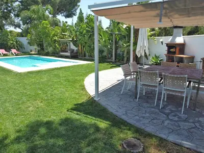a table and chairs under an umbrella next to a pool at Villa Edén, Casa Rural lujo con Chimenea Piscina in Arcos de la Frontera