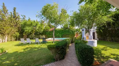 a backyard with a swimming pool and chairs and trees at Villa El Cortijo Andaluz Conil de la Frontera by Ruralidays in Conil de la Frontera