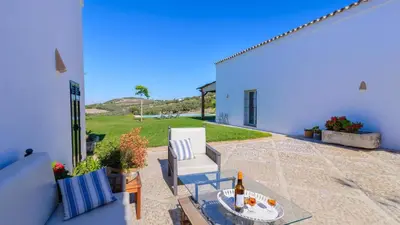 a patio with a chair and a table with a bottle of wine at Finca Las Encinillas Arcos de la Frontera by Ruralidays in Arcos de la Frontera