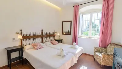 a bedroom with two beds and a chair and a window at Finca Las Encinillas Arcos de la Frontera by Ruralidays in Arcos de la Frontera