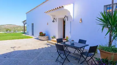 a table and chairs in front of a white house at Finca Las Encinillas Arcos de la Frontera by Ruralidays in Arcos de la Frontera