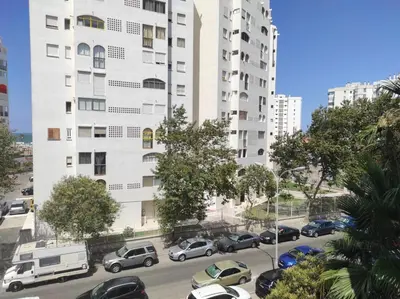 a large white building with cars parked in a parking lot at APARTAMENTO GENOVEVA PLAYA - Playa, Piscina, Wifi in El Puerto de Santa María