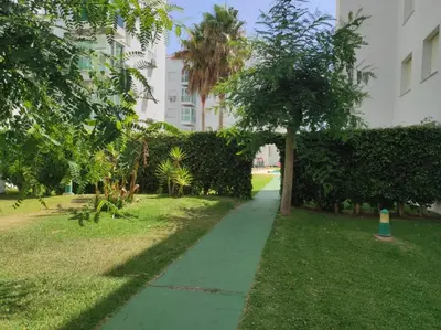 a sidewalk in a park with a tree and a building at APARTAMENTO GENOVEVA PLAYA - Playa, Piscina, Wifi in El Puerto de Santa María