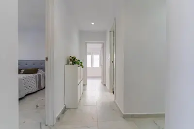 a hallway with white walls and a bedroom with a bed at Casita de la coquina in Chiclana de la Frontera