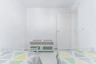 a white room with two beds and a dresser at Casita de la coquina in Chiclana de la Frontera