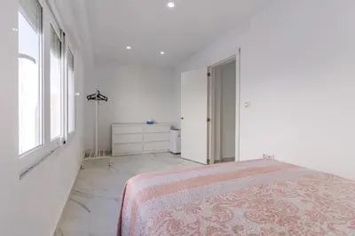 a white bedroom with a bed and a window at Casita de la coquina in Chiclana de la Frontera