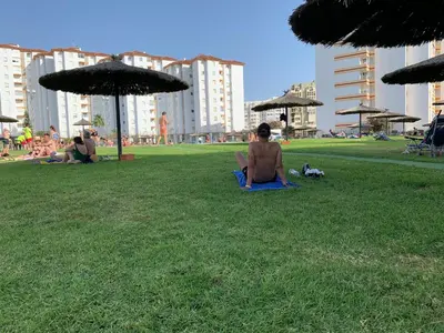 a man sitting on the grass in a park at Apartamento playa Valdelagrana in El Puerto de Santa María