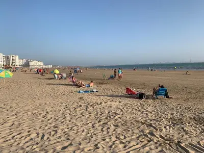 a group of people sitting on a beach at Apartamento playa Valdelagrana in El Puerto de Santa María