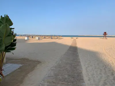 a boardwalk on a beach with people in the background at Apartamento playa Valdelagrana in El Puerto de Santa María