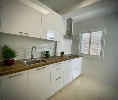 a kitchen with white cabinets and a sink and a window at MyChoice Carmen in Rota