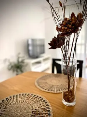 a wooden table with a vase with flowers in it at MyChoice Carmen in Rota