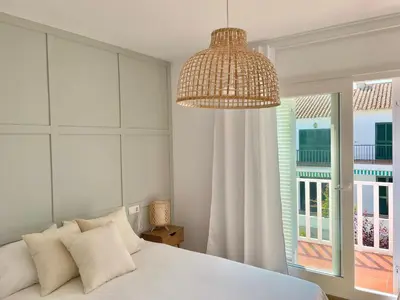 a bedroom with a white bed and a large chandelier at Adosado en calle Nereida in Chiclana de la Frontera