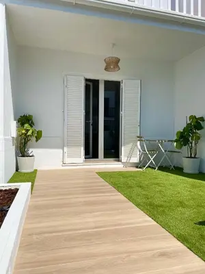 a white house with a porch with a green lawn at Adosado en calle Nereida in Chiclana de la Frontera