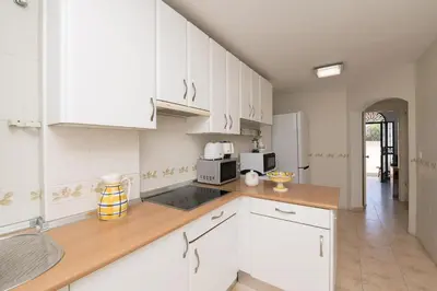 a kitchen with white cabinets and a wooden counter top at Los Jandalos in El Puerto de Santa María