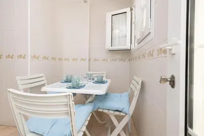 a small dining room with a white table and chairs at Los Jandalos in El Puerto de Santa María
