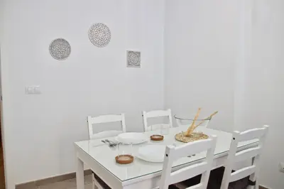 a white dining room with a white table and chairs at Apartamento San Leonardo Playa (Free Parking) in Cádiz